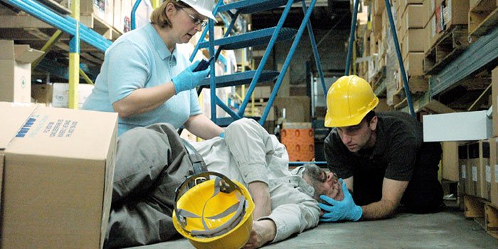 workers providing first aid to injured co-worker