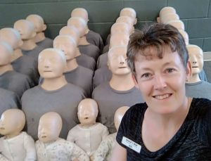 First aid instructor in foreground with CPR manikins behind