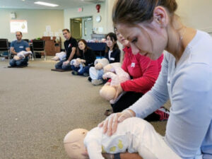 A first aid course student holding a baby CPR manikin. Emergency Child Care First Aid FAQs