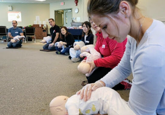 A first aid course student holding a baby CPR manikin. Emergency Child Care First Aid FAQs